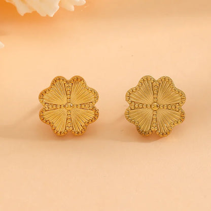 Pair of gold floral earrings on a beige background