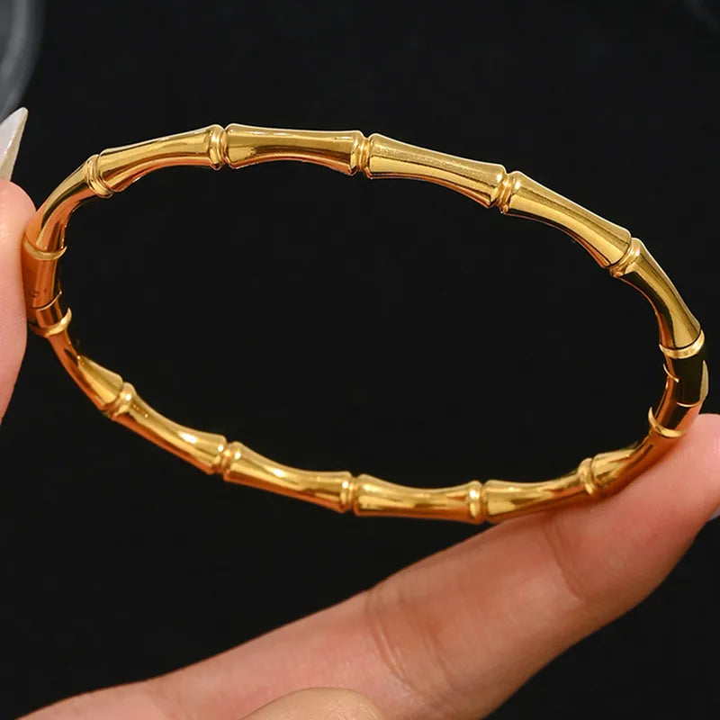 Gold bracelet held on a hand against a black background