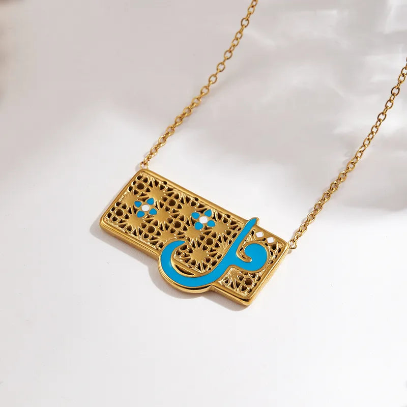 Gold necklace with a rectangular pendant featuring Arabic calligraphy in blue on a white background