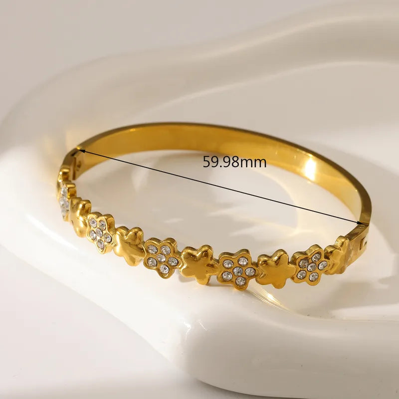 Gold bracelet with floral design and measurement on a white background