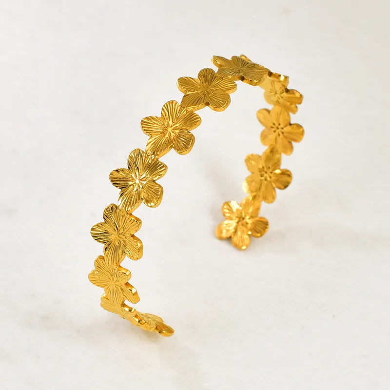 Gold floral hoop earrings on a light gray background