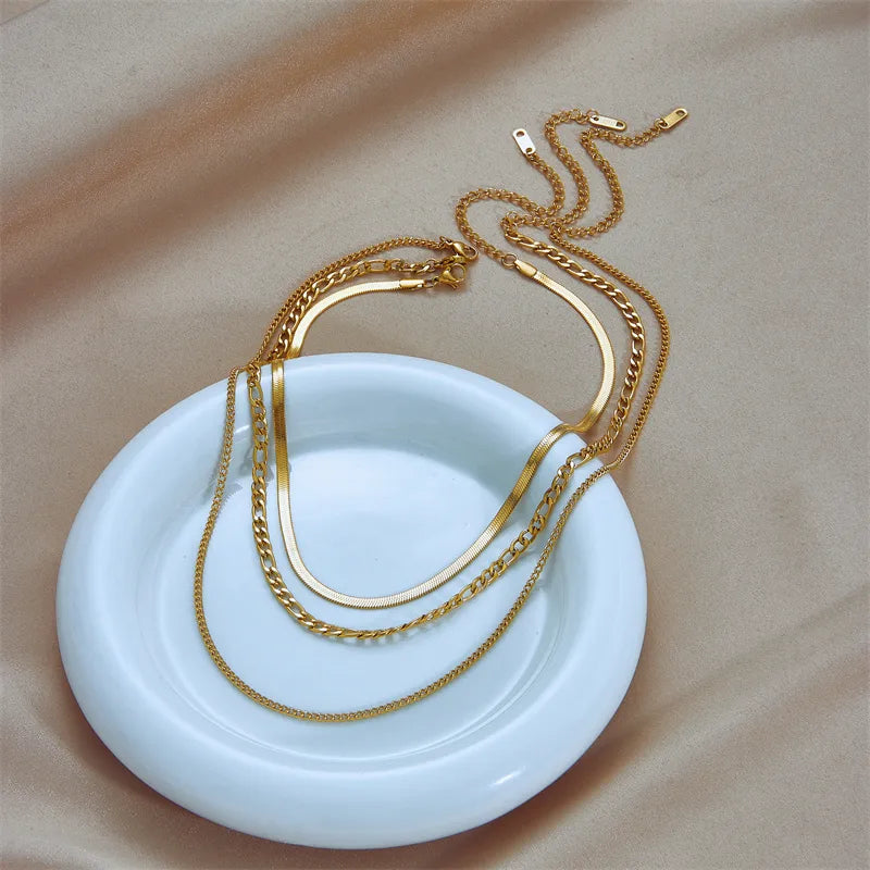 Gold necklaces on a white dish with a beige background