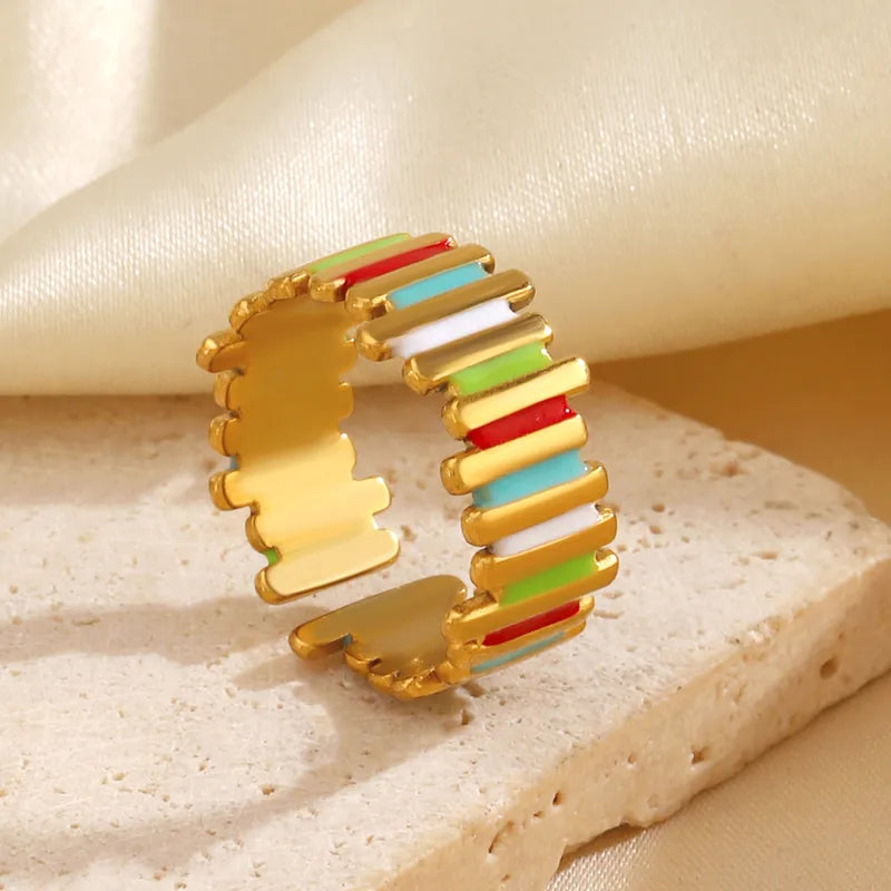 Colorful hoop earring with gold frame on a textured beige surface
