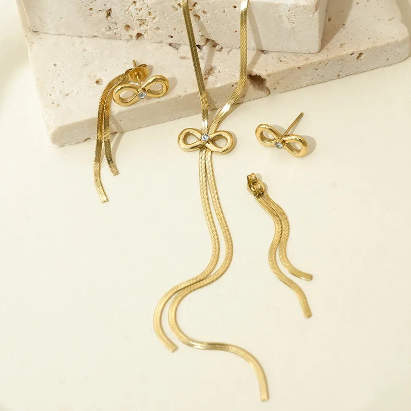 Gold bow-shaped earrings on a textured surface