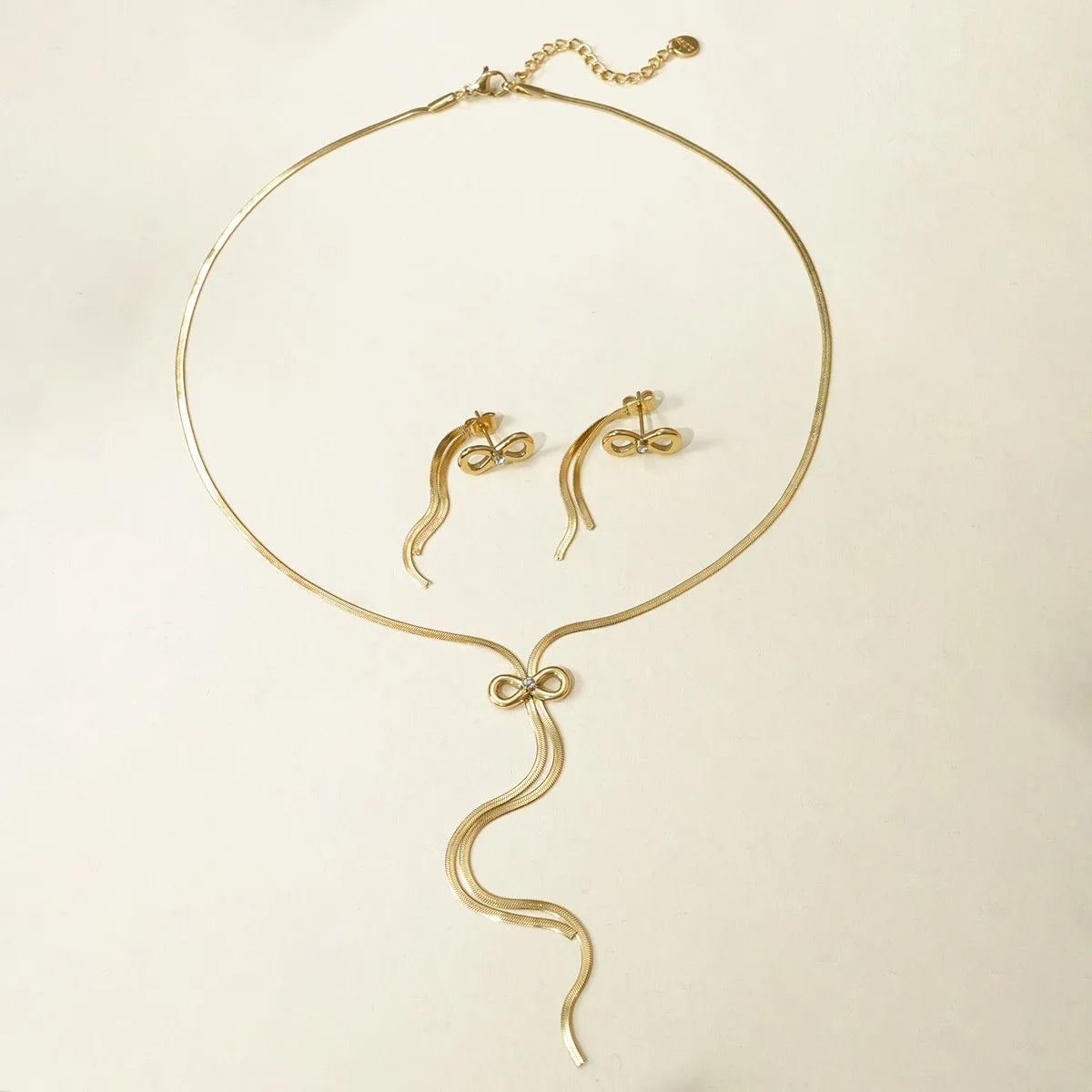 Gold necklace and earrings set on a beige background