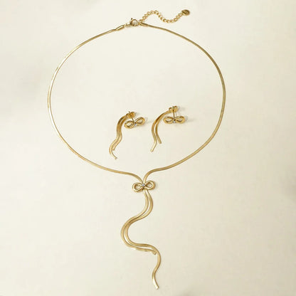 Gold necklace and earrings set on a beige background