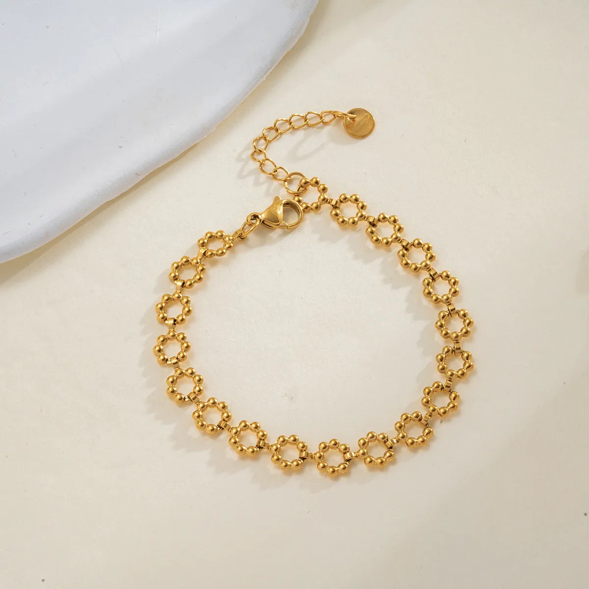 Gold chain bracelet on a light beige surface