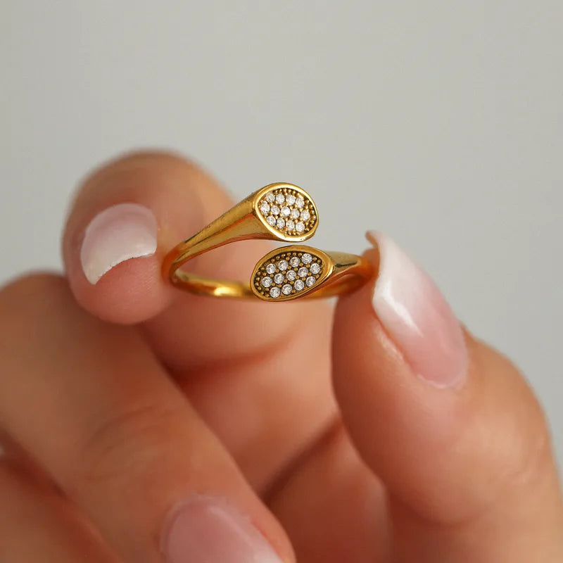 Gold ring with diamond accents on a finger against a neutral background