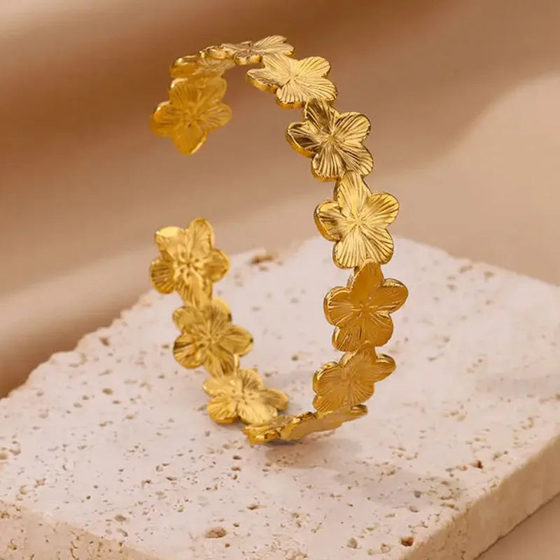 Gold floral hoop earrings on a textured beige surface