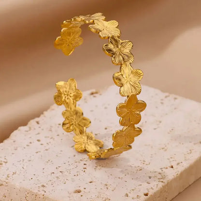 Gold floral hoop earrings on a textured beige surface