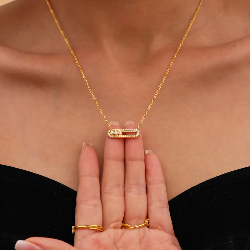 Gold necklace and ring set on a person's hand with a neutral background