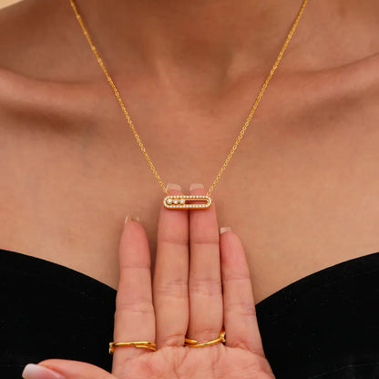 Gold necklace and ring set on a person's hand with a neutral background