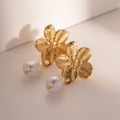 Gold flower-shaped earrings with pearls on a light background