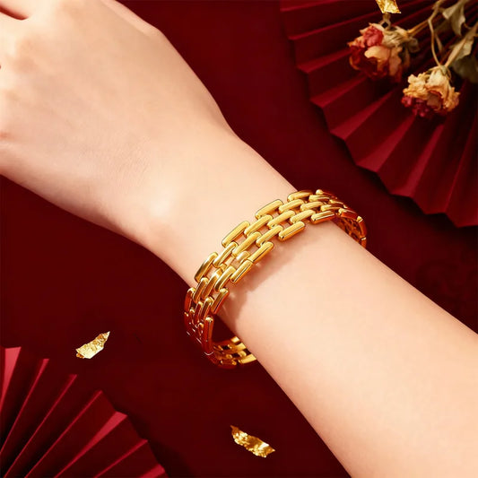 Gold bracelet on a wrist with a red background