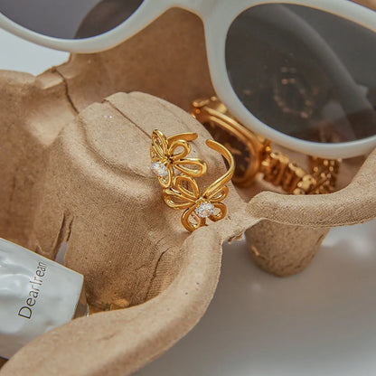 Gold ring with leaf design on a beige fabric background
