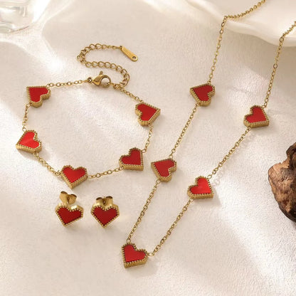 Gold necklace with red heart pendants on a white surface
