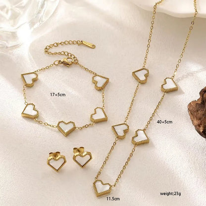 Gold heart-shaped jewelry set including necklace, bracelet, and earrings on a light background.
