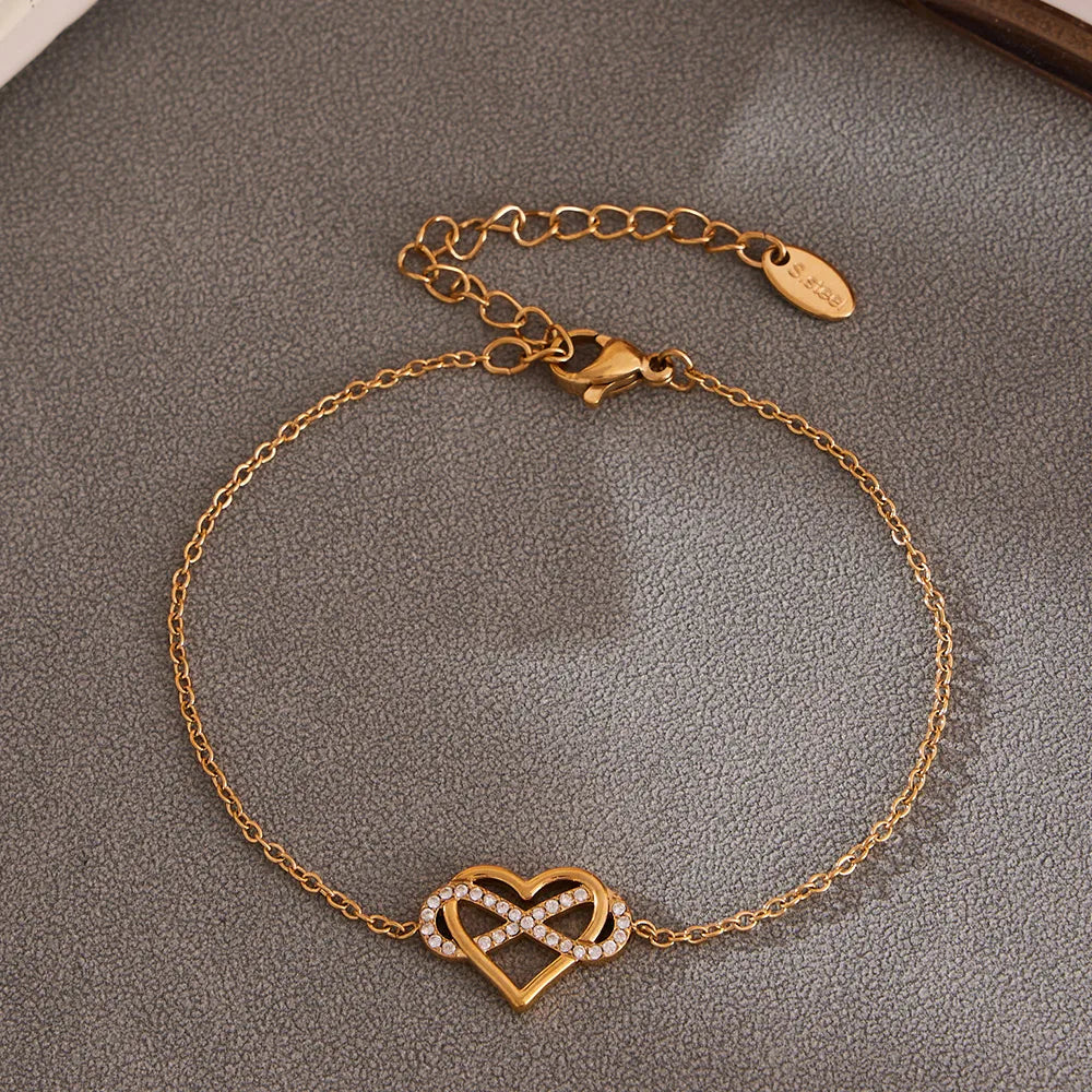 Gold bracelet with heart and infinity symbol on a gray surface
