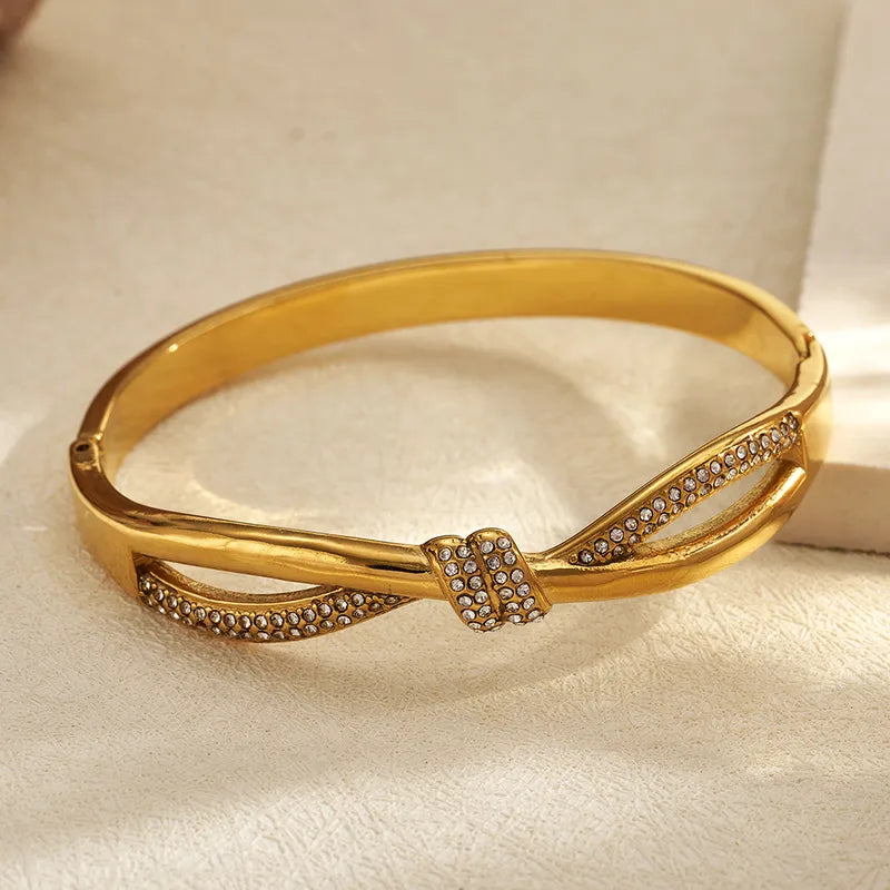 Gold bracelet with diamond accents on a light fabric background