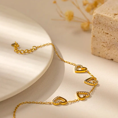 Gold heart-shaped bracelet on a neutral background