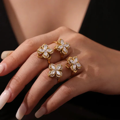 Hand wearing three gold rings with diamond-like stones on a dark background