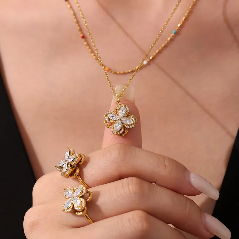 Gold butterfly necklace and earrings on a person's hand against a black background