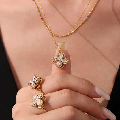 Gold butterfly necklace and earrings on a person's hand against a black background