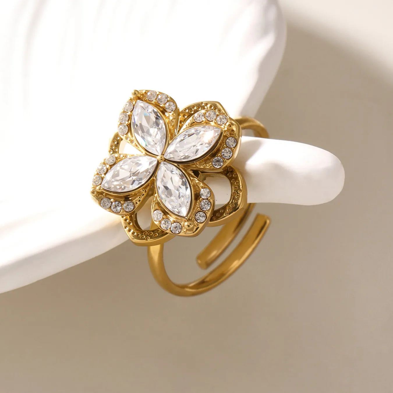 Gold ring with floral design and clear gemstones on a white background