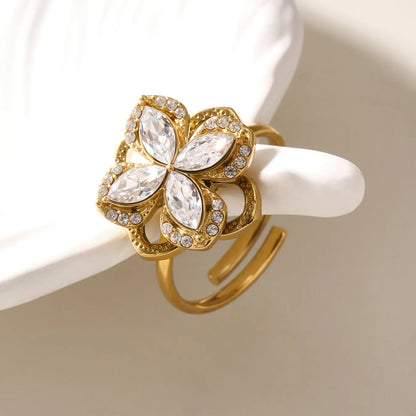 Gold ring with floral design and clear gemstones on a white background
