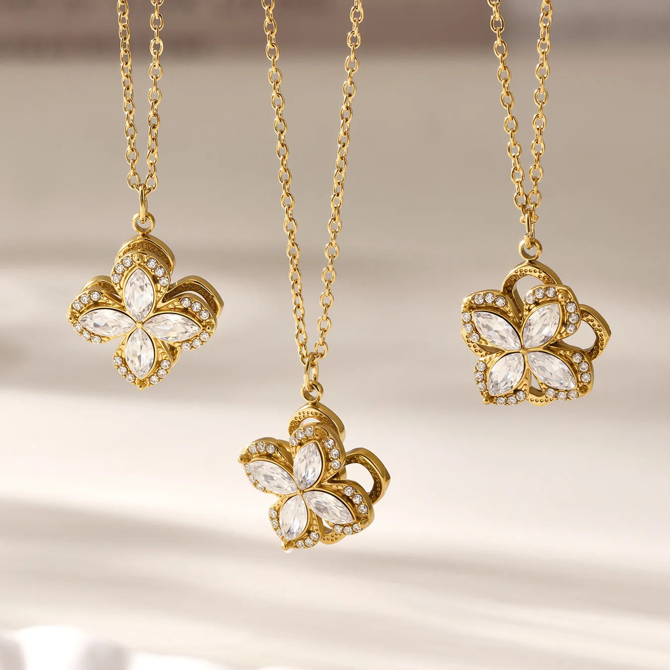 Three gold butterfly necklaces with gemstones on a neutral background