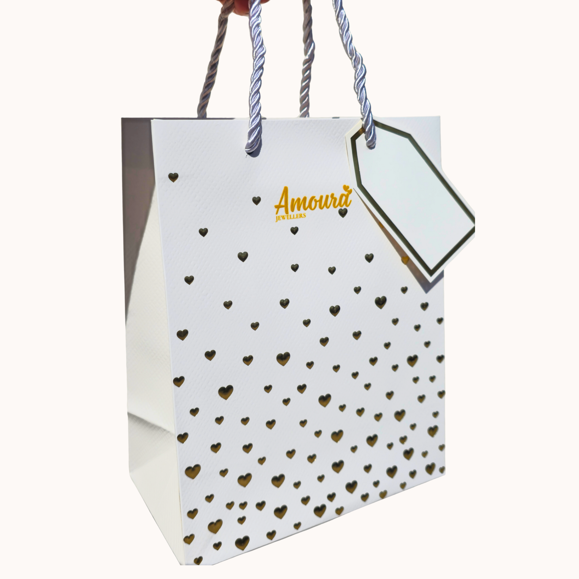 White gift bag with gold heart patterns and 'Amoura' branding on a white background