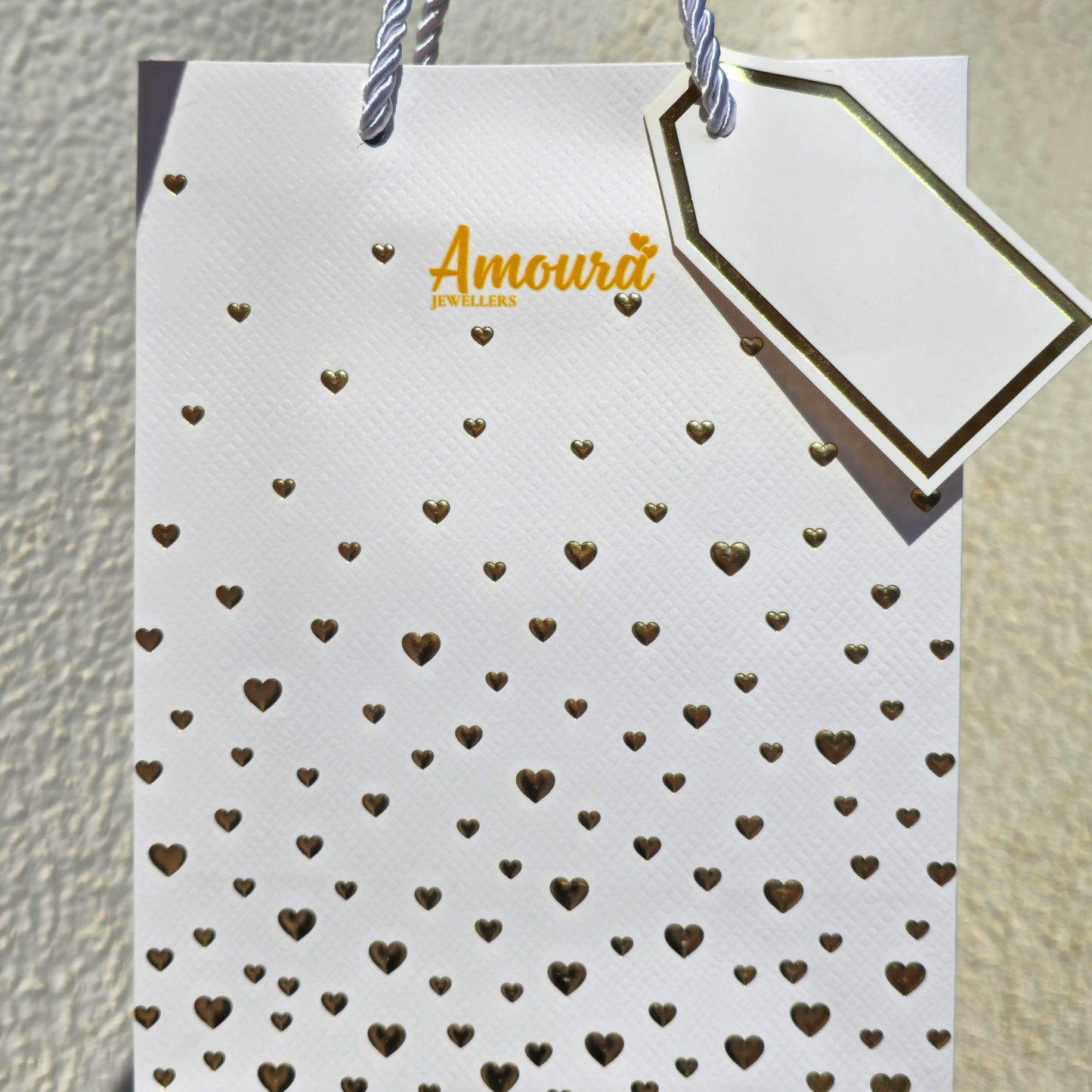 White card with gold heart patterns and a gold tag on a textured beige background
