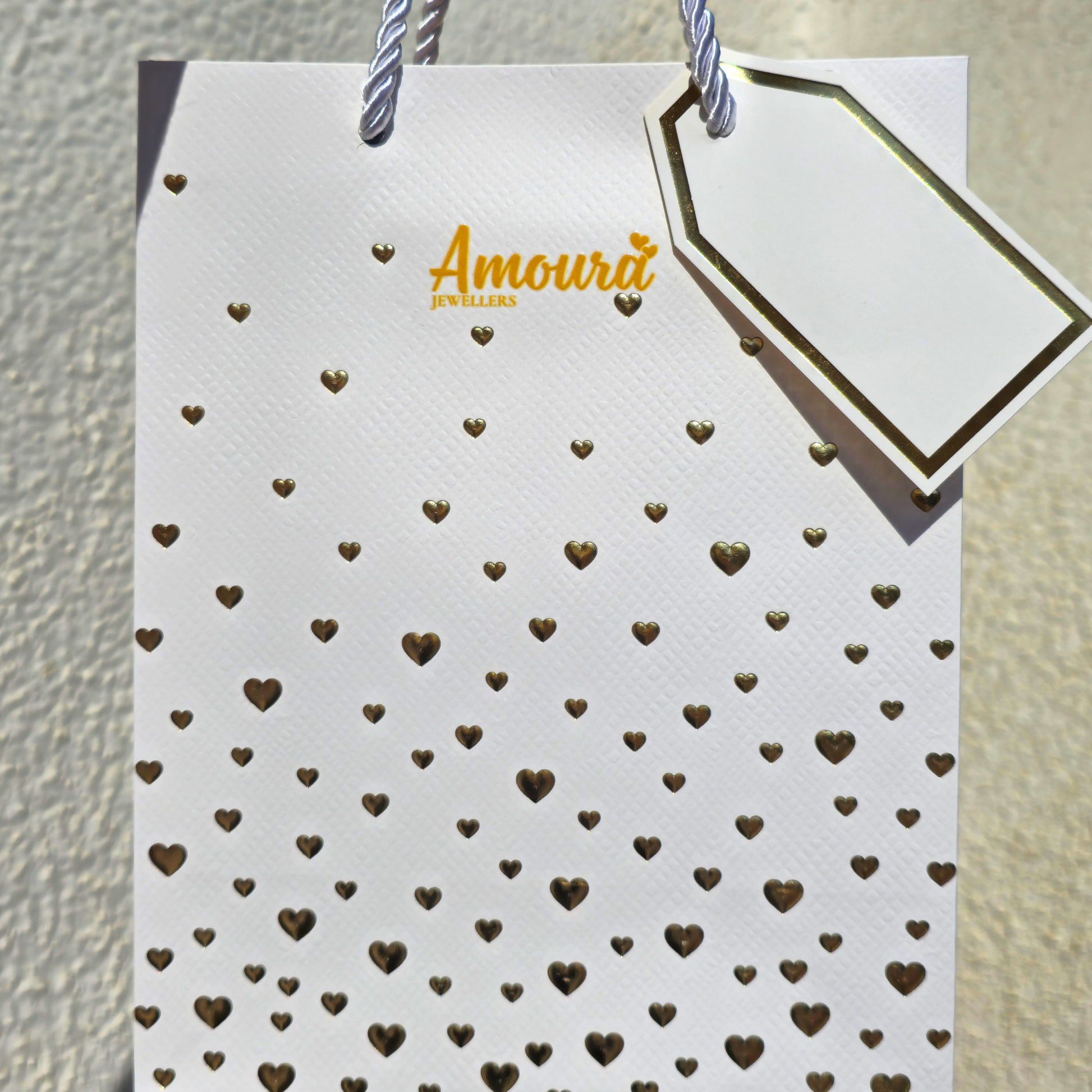 White card with gold heart patterns and a gold tag on a textured beige background