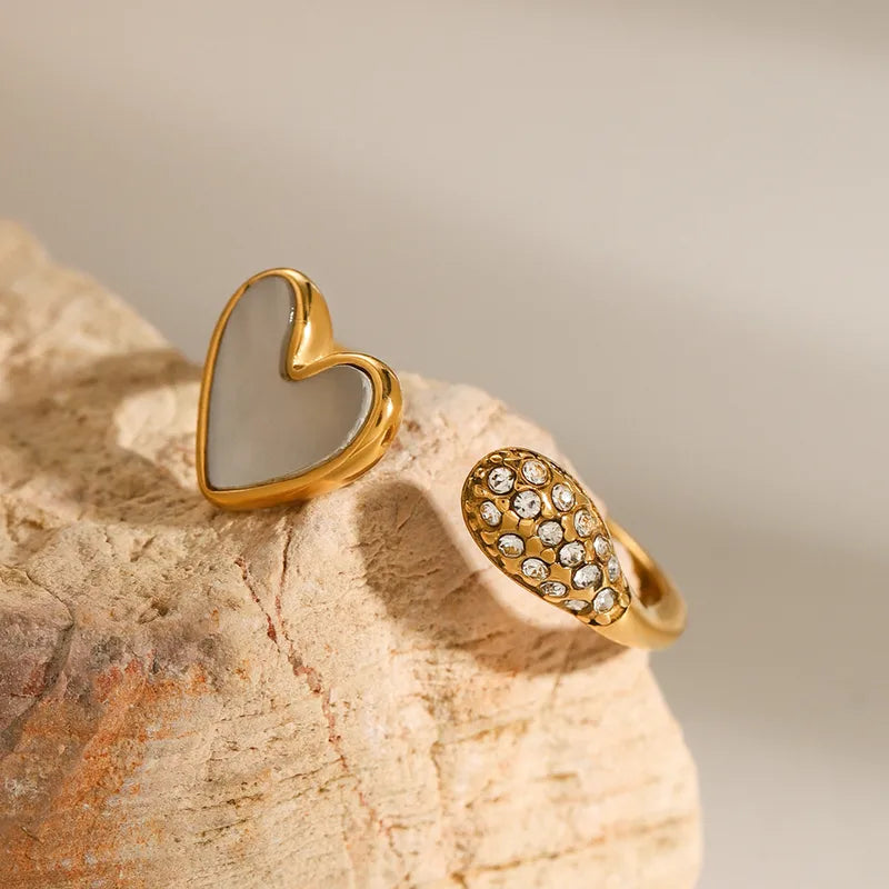 Two gold heart-shaped rings on a textured stone surface with a blurred background