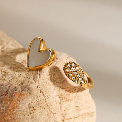 Two gold heart-shaped rings on a textured stone surface with a blurred background