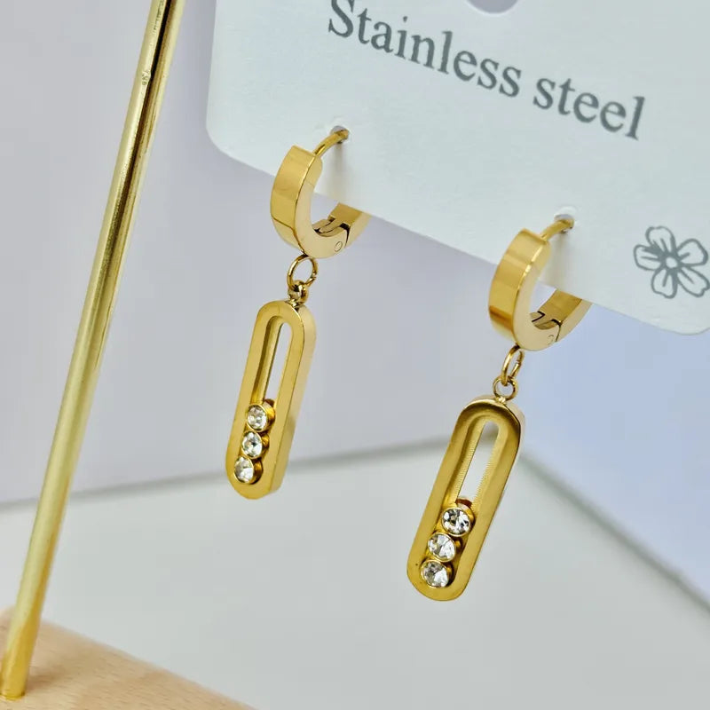 Gold hoop earrings with dangling rectangular charms on a white background