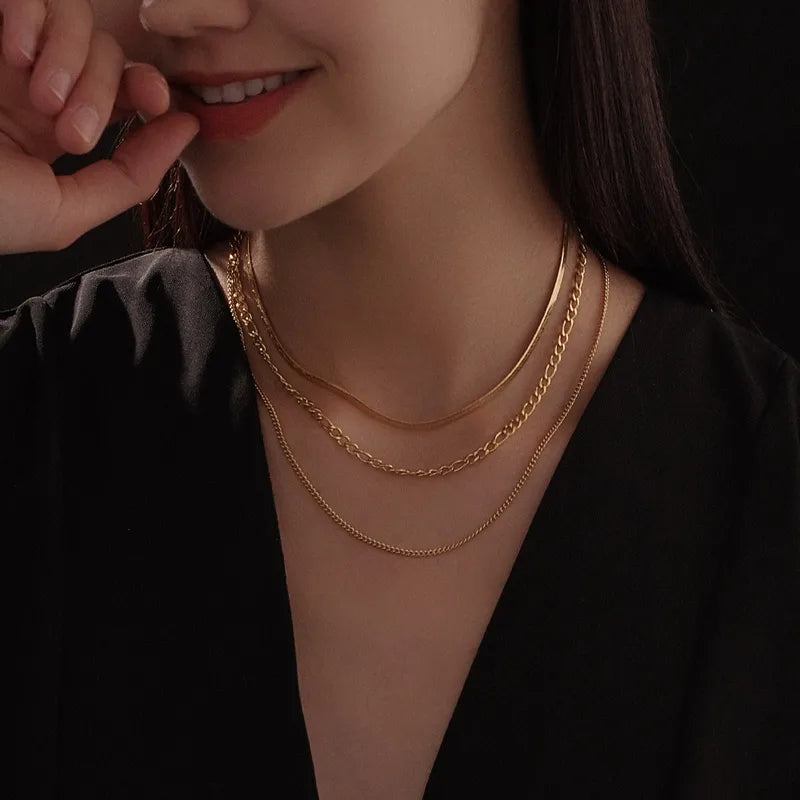 Woman wearing a gold necklace with a dark background