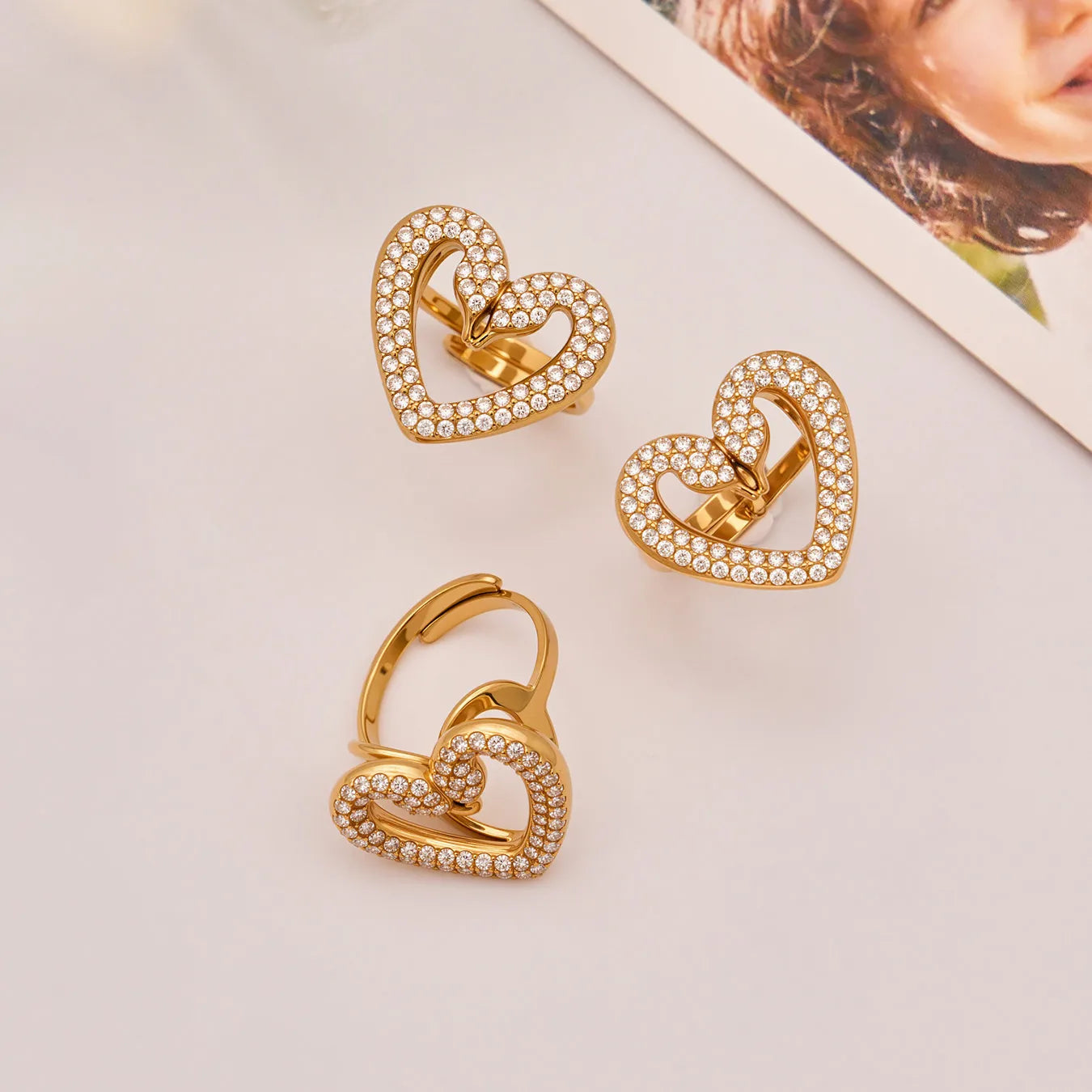 Gold heart-shaped earrings with embedded stones on a light surface.