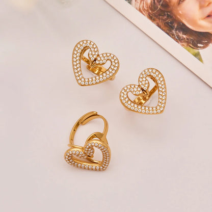 Gold heart-shaped earrings with embedded stones on a light surface.