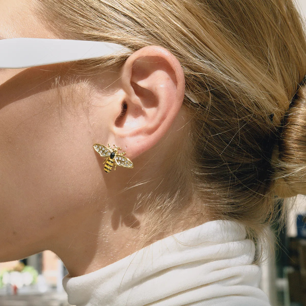 Close-up of a person wearing a gold bee-shaped earring.