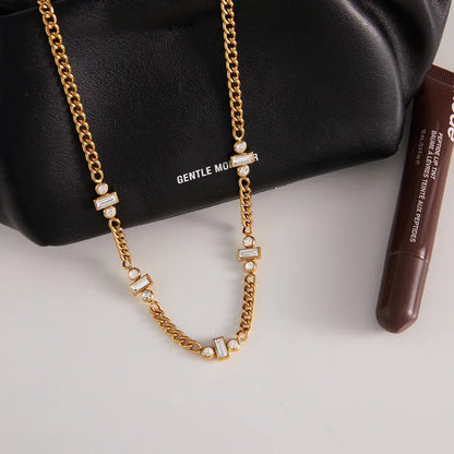 Gold chain necklace on a black handbag with 'Gentle Monster' branding.
