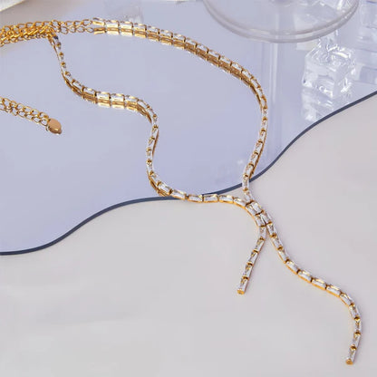 Gold chain necklace on a light gray surface