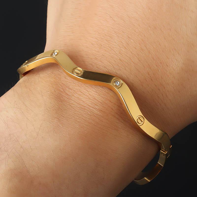 Gold bracelet on a wrist with a dark background