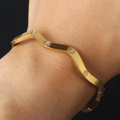 Gold bracelet on a wrist with a dark background